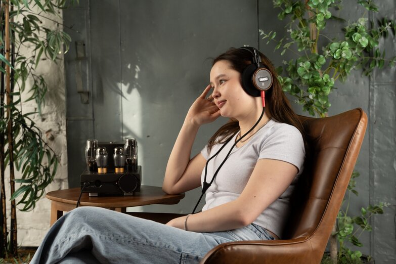 A woman with S550 headphones on is sitting in a chair 