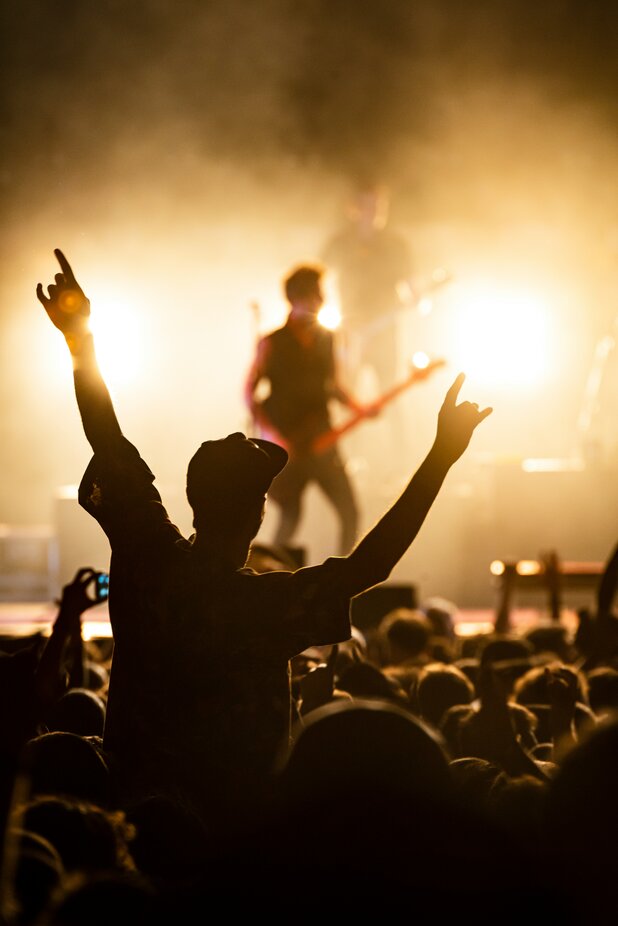 Man in crowd at a concert holding both arms up 