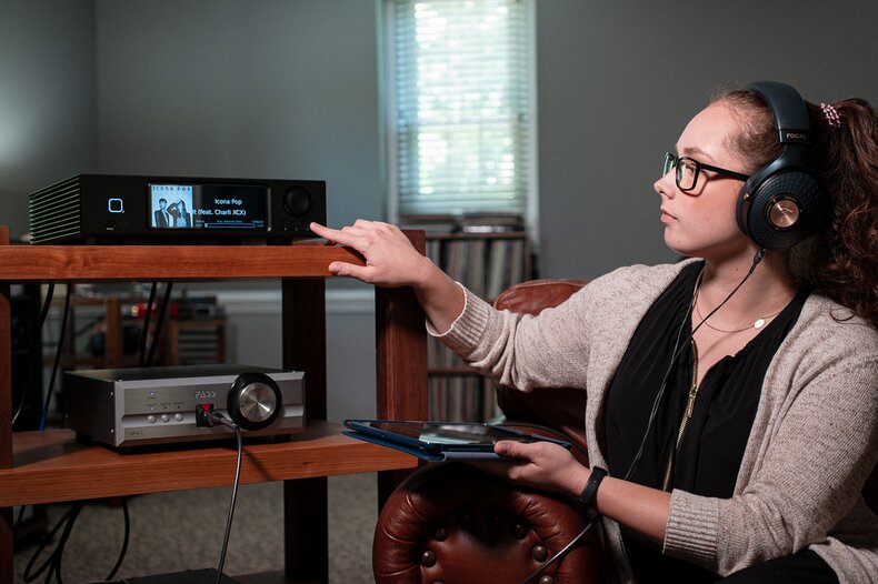 individual wearing the focal celestee headphones while touching the aurender a200 caching network streamer