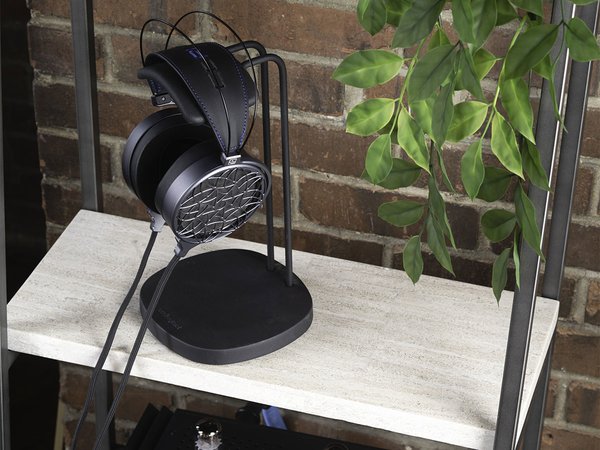 COINA Electrostatic Headphones by Dan Clark Audio, hanging from a stand on a shelf next to a plant, top looking down perspective.