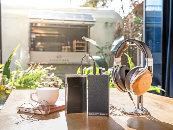 Astell&Kern PA10 Amp lifestyle shot on a table with a cup of tea and book, a music player, and headphones.