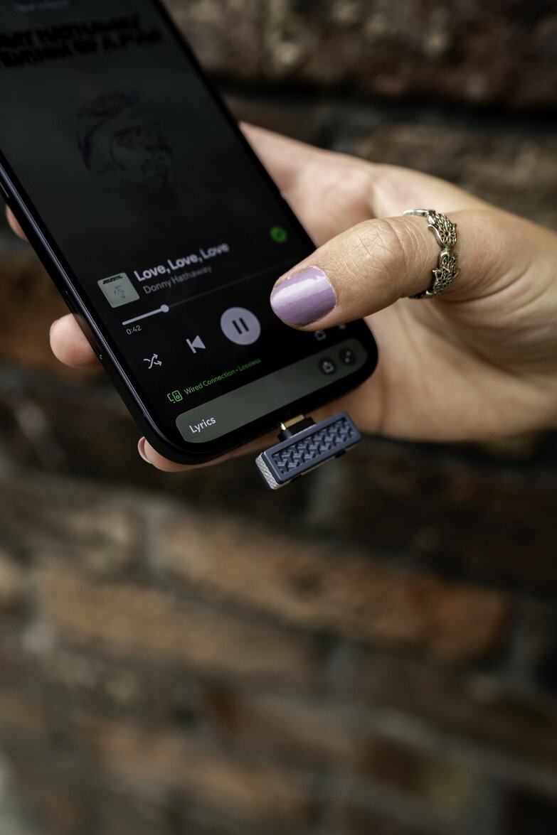 Close-up of hand on phone controlling spotify with transmitter plugged in usb