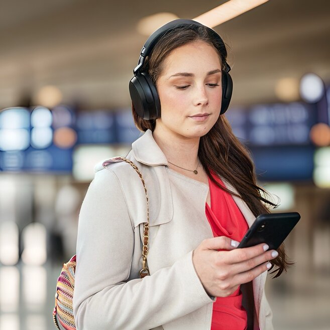 woman listening to headphones in an airport