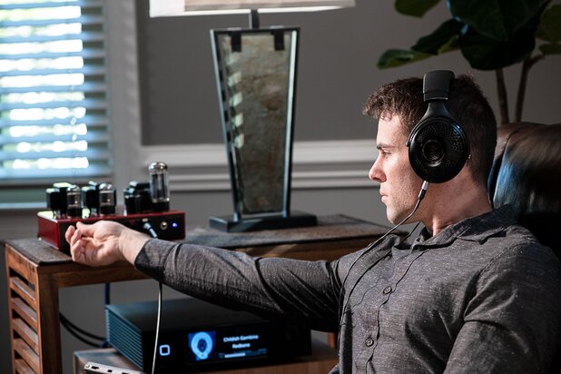 Man wearing headphones adjusting volume on amplifier 