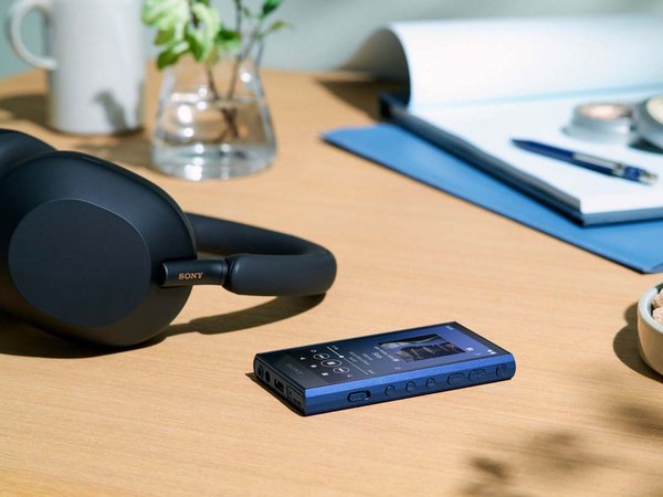 Sony NW-A306 Walkman Music player, sitting on a table with headphones and a journal in the background.