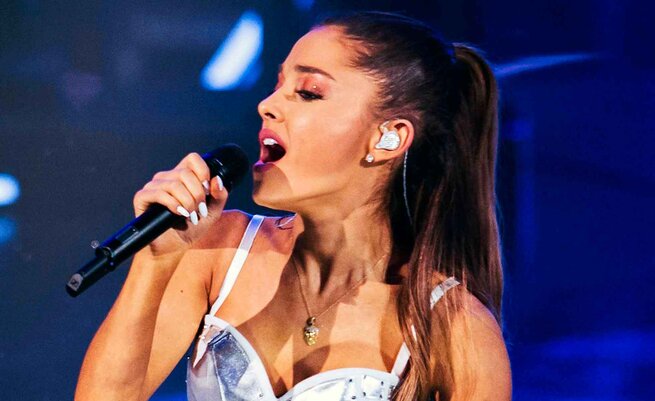 Ariana Grande holding a microphone and wearing IEMs