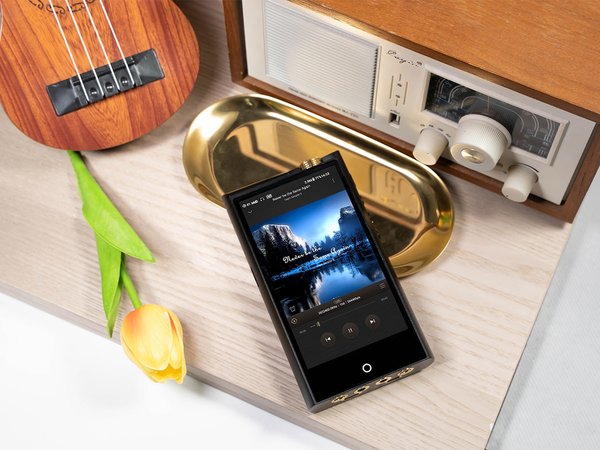 N7 DAP music player by Cayin on a table next to a speaker, musical instrument, and tulip flower.