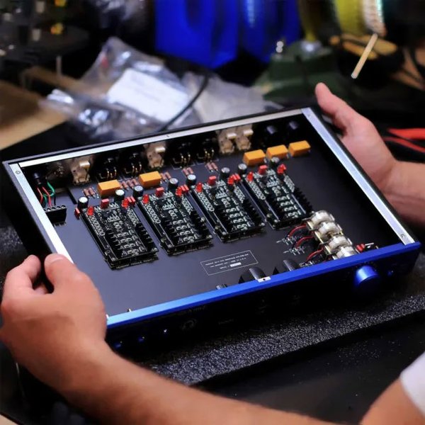 Hands holding an open console showing circuit boards for the HeadAmp GS-X mk2 amplifier.