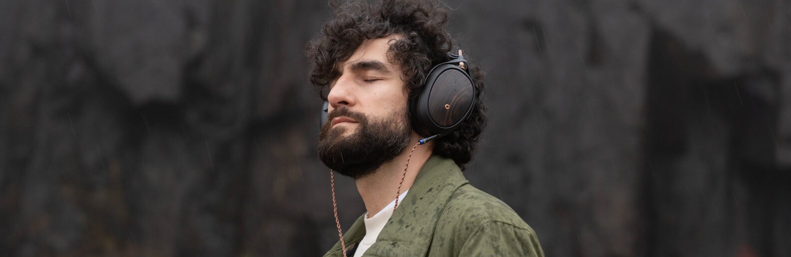 Liric 2 on man with eyes closed immersed in sound with charcoal background