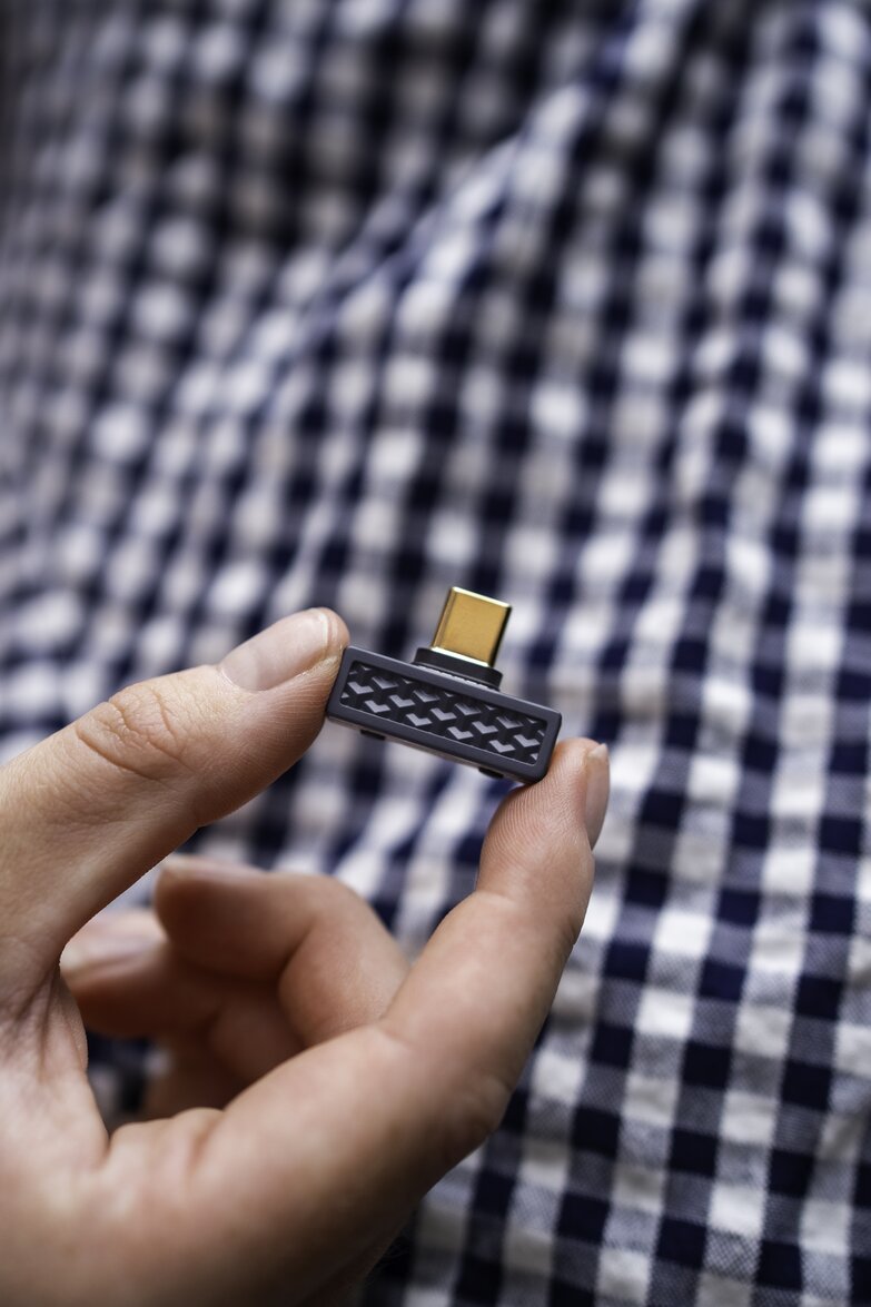transmitter between fingers close up in front of plaid shirt