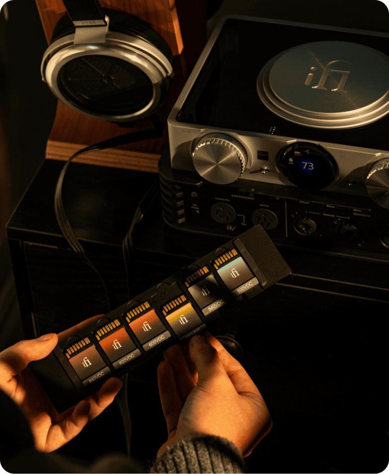 Ican phantom 1.5 setup next to headphones with hand looking at different voltage cards