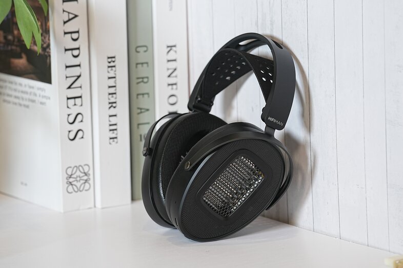 Arya WIFI Streaming Media Planar Headphone leaning against the wall on the counter beside the books 