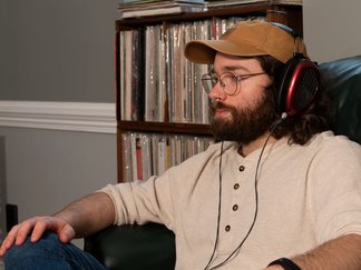 man listening with headphones in front of vinyl records