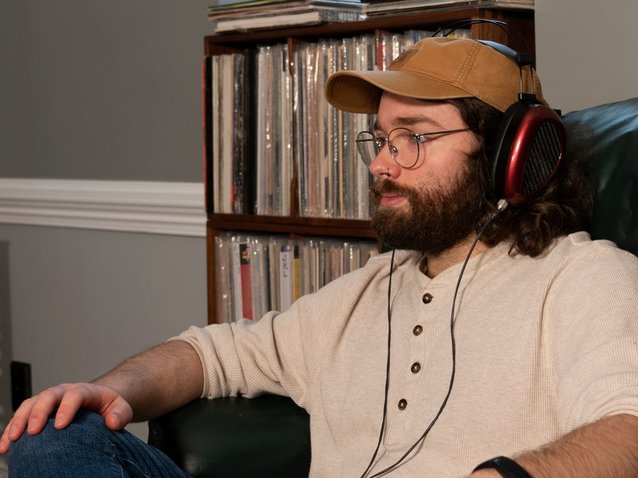 man listening with headphones in front of vinyl records