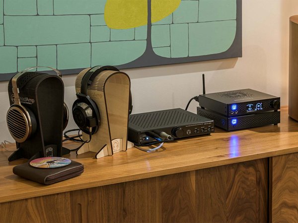 HeadAmp GS-X Mini Headphone Amp sitting on a table next to other audio equipment and headphones.