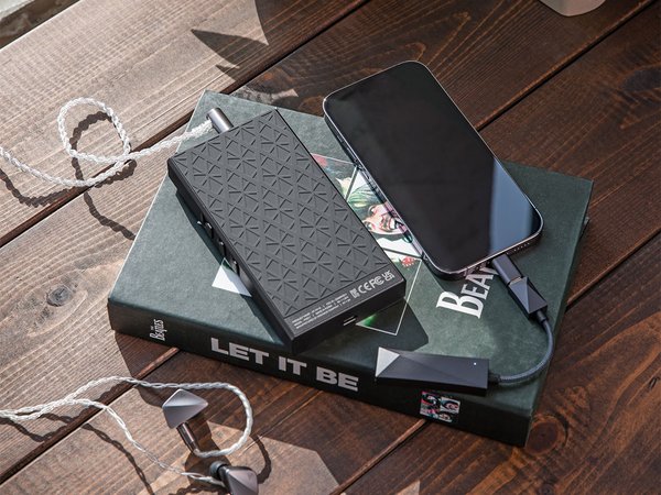 Astell&Kern PA10 Amp resting on top of a book, sitting on a table with a music player and IEMs.