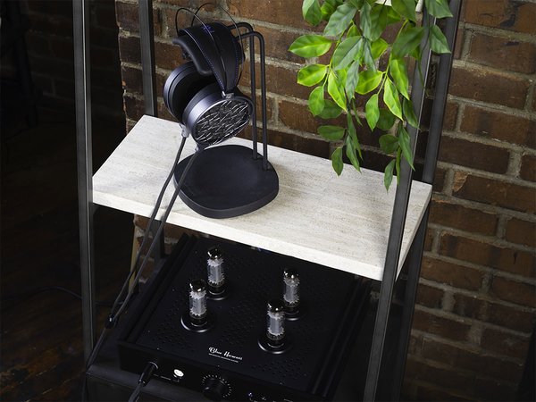 COINA Electrostatic Headphones by Dan Clark Audio, hanging from a stand on a shelf next to a plant, with an amplifier on the shelf below.