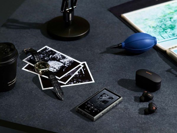 Sony NW-A306 Walkman Music Player sitting on a table with IEMs and printed photos.