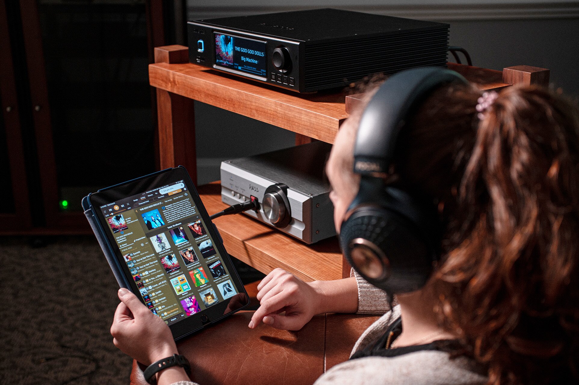 Woman wearing headphones holding an Apple iPad with screen illluminated