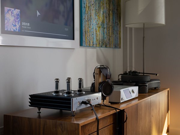 The Blue Hawaii SE by HeadAmp sitting on a table with headphones and other audio equipment in a home setting.
