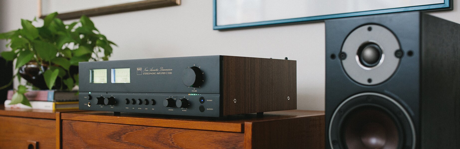 NAD Electronics C3050 Stereophonic amplifier on a table next to speakers