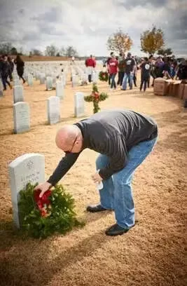 Man placing flowers on veteran's tombstone