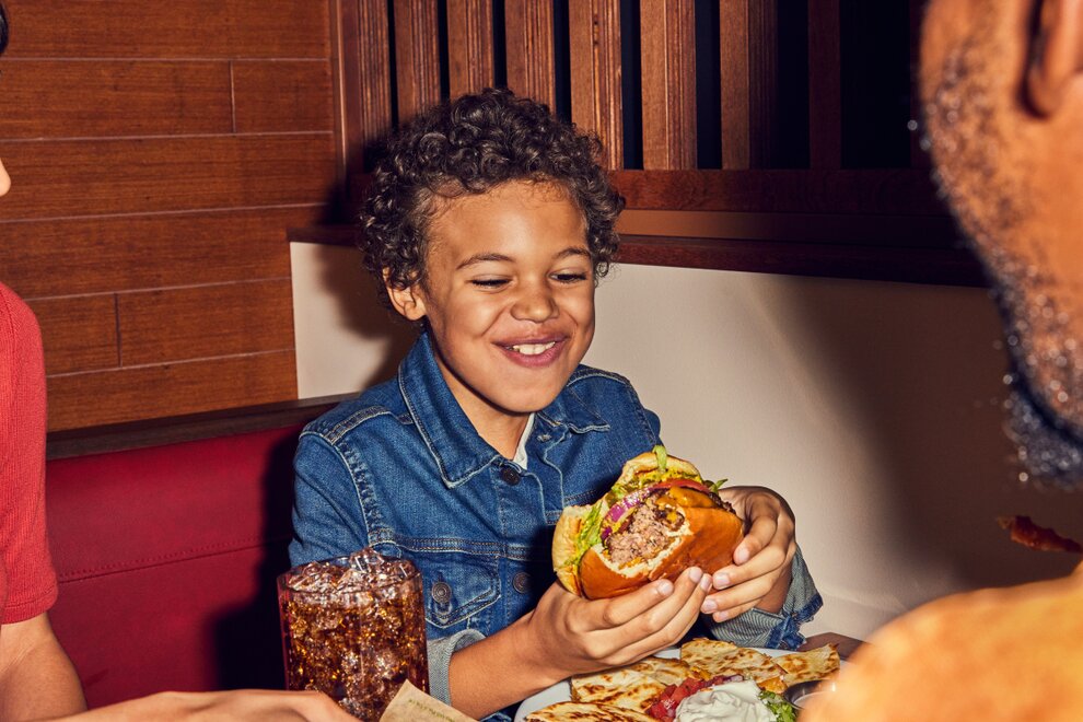 Little boy eating burger at Chili's where Kids Eat Free