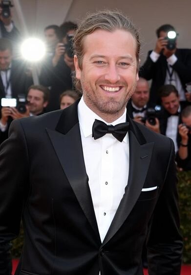 AI movie star generator image showing a man in a tuxedo with red carpet lighting and photographers in the background.