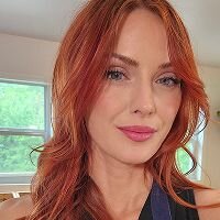 Portrait of the same woman with long auburn hair and a natural smile in casual attire.
