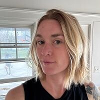 Unedited photo of a woman with chin-length blonde hair, taken indoors—used as a reference for AI period costume transformation.