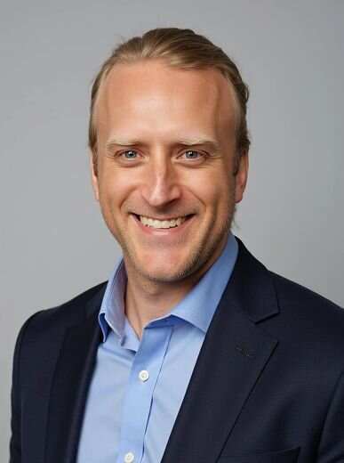 AI-generated church staff portrait of a man in a navy suit and light blue shirt, smiling against a soft neutral background.