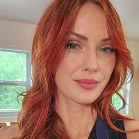 Casual reference photo of a red-haired woman taken indoors—used as a starting point for Somny’s professional AI headshot transformation.