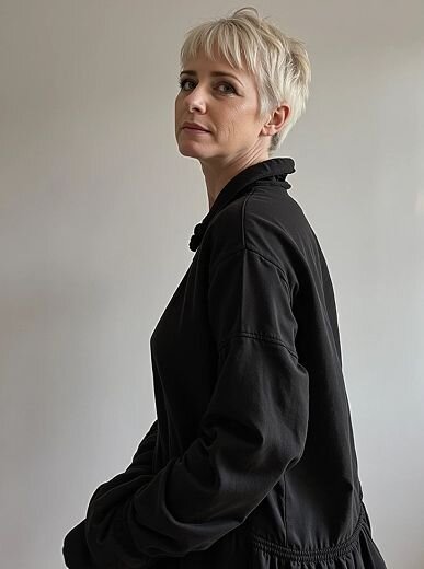 AI fashion portrait of a woman with slicked-back hair in a dark high-collar outfit, posing against a solid gray studio backdrop.
