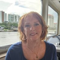 Original photo of an older woman smiling at a riverside restaurant, used as the starting point for Somny’s AI travel portrait transformation.
