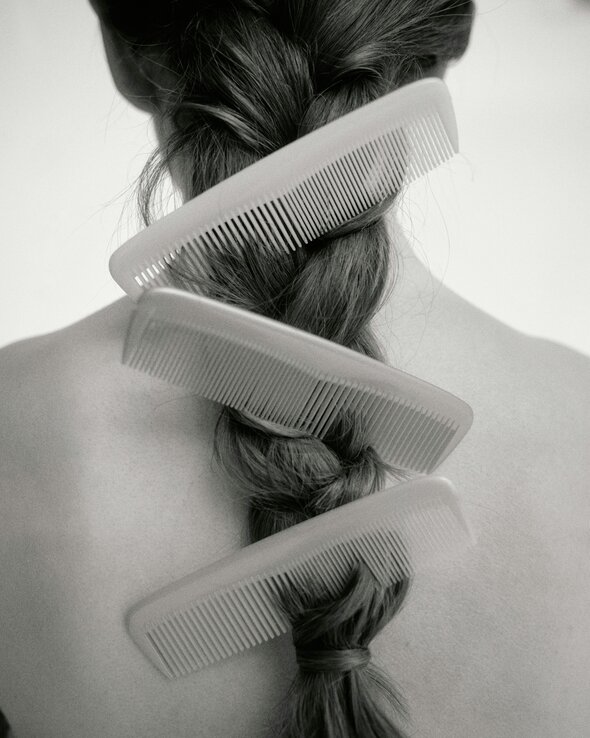 Spark Stories: Human Material Loop - back of a woman's head with hair in a single braid. 3 combs hang off the braid