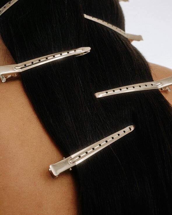 Spark Stories: Human Material Loop - back of a woman's head with wavy black hair and 4 clips going down the length of the hair