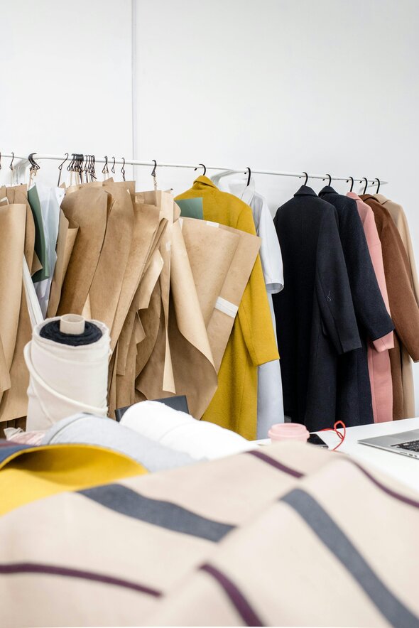 Ace the ESPR: A Guide for Designers & Buyers. Clothing rail of multi-coloured trench coats. 