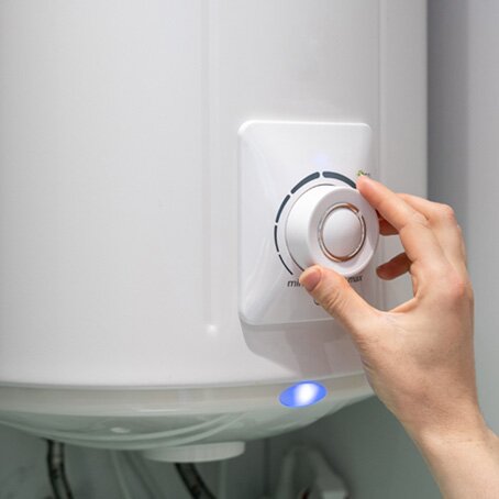 hand adjusting dial of white natural gas water heater