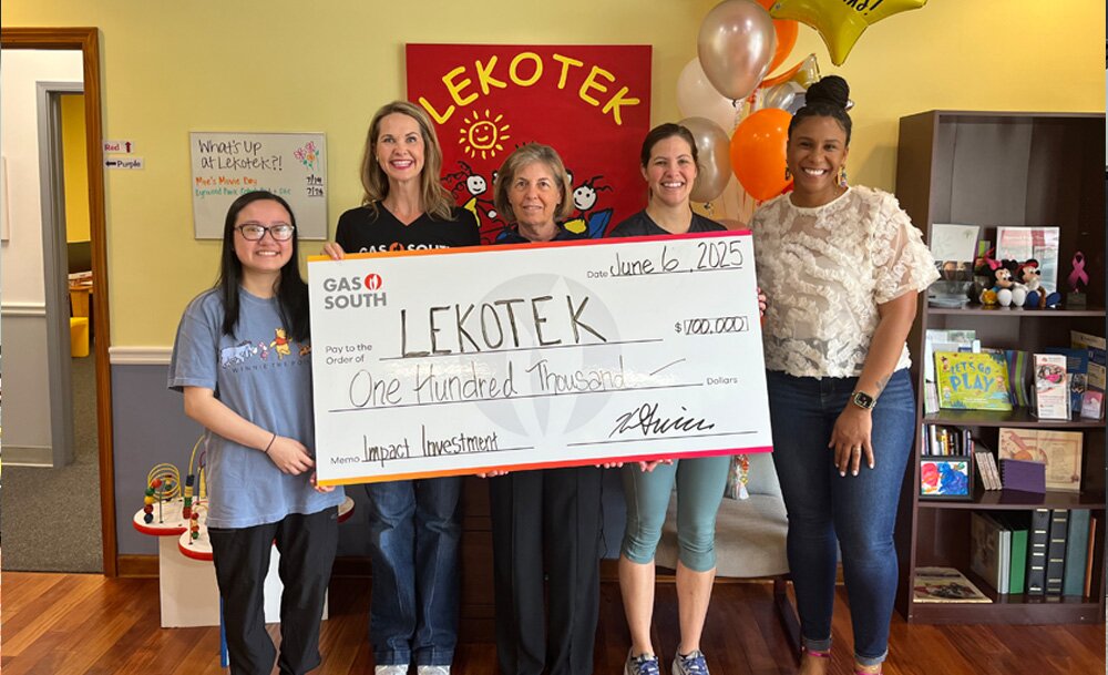 people surrounding a large donation check inside of a nonprofit organization 