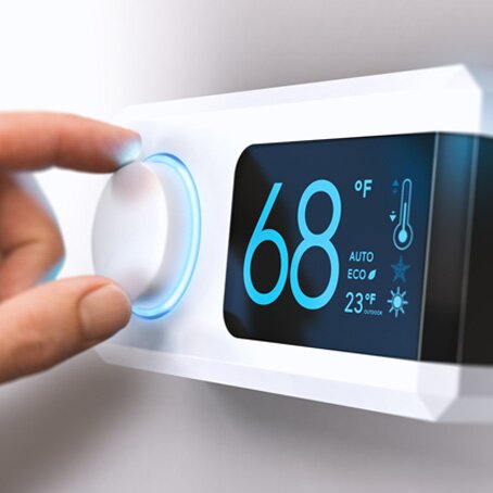 person adjusting a digital thermostat to 68 degrees