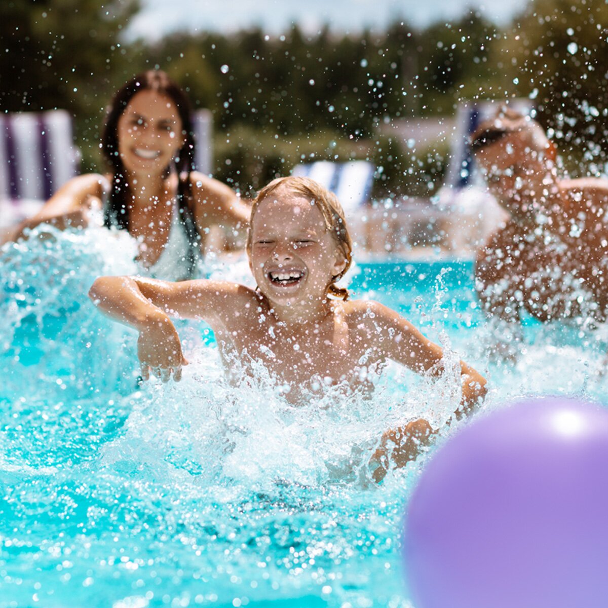 three people splash happily in a heated pool