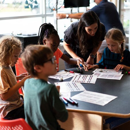 teacher in classroom teaching elementary school children around a table