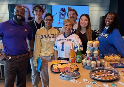 Gas South employees in front of food and cupcakes in concession area of the office