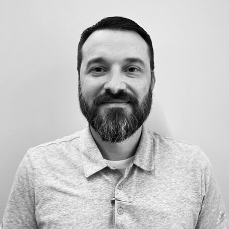 black and white portrait of man with beard in a light-colored button up shirt