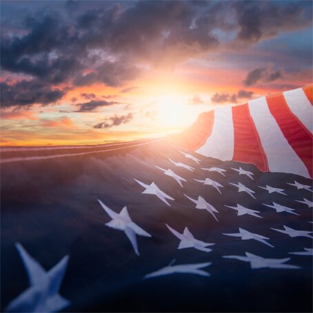 American flag waving in front of a sunset