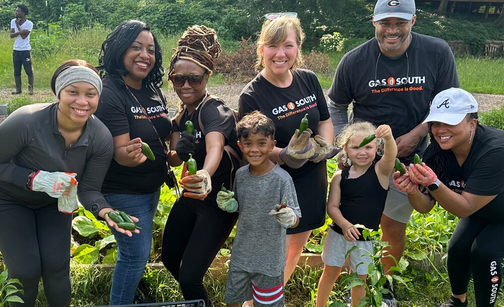 Gas South employee volunteers with kids in the community showing the jalapenos they picked