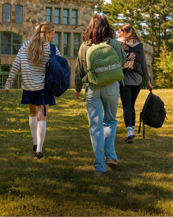 Students walking across campus carrying backpacks. Shop backpacks.