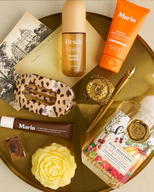 Assorted beauty and skincare products arranged on a gold tray.