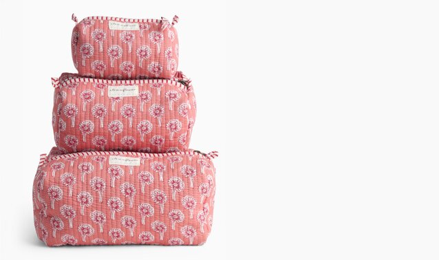 Three pink floral quilted cosmetic bags in coordinating sizes stacked on a white background.