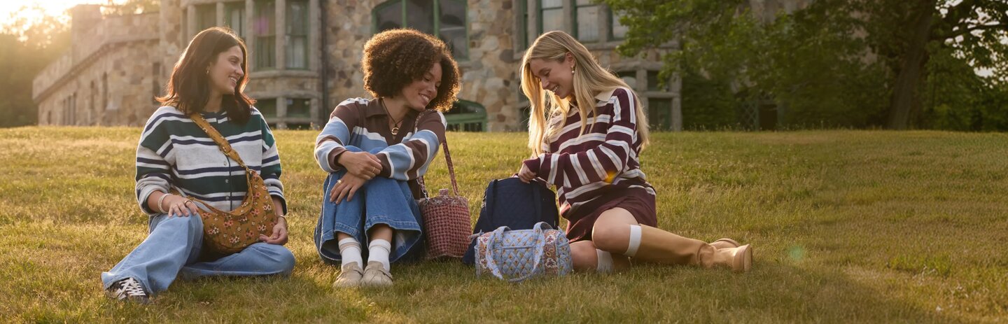 Three women sitting outdoors with Vera Bradley bags. Save 25% on Vera Bradley totes, bags and crossbodies, in-store and online.